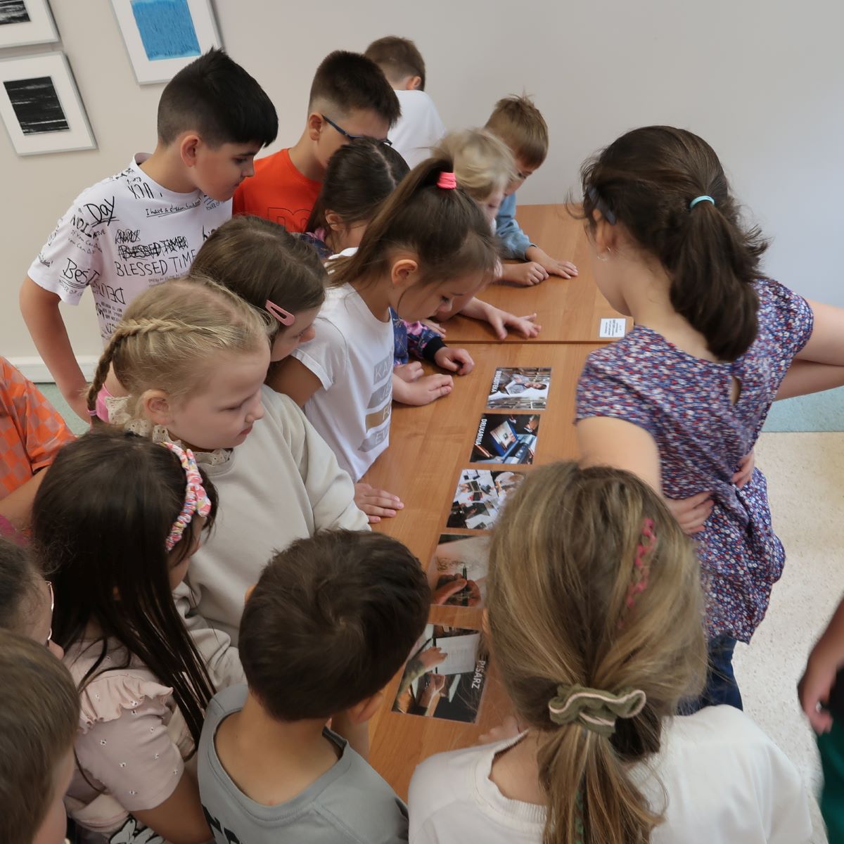 Dzieci przyglądają się zdjęciom rozłożonym na stole