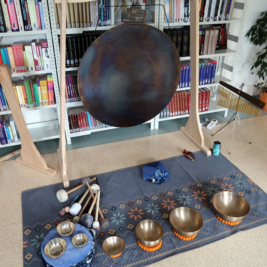 Na dywanie rozłożone są pałeczki i grające misy różnego rozmiaru