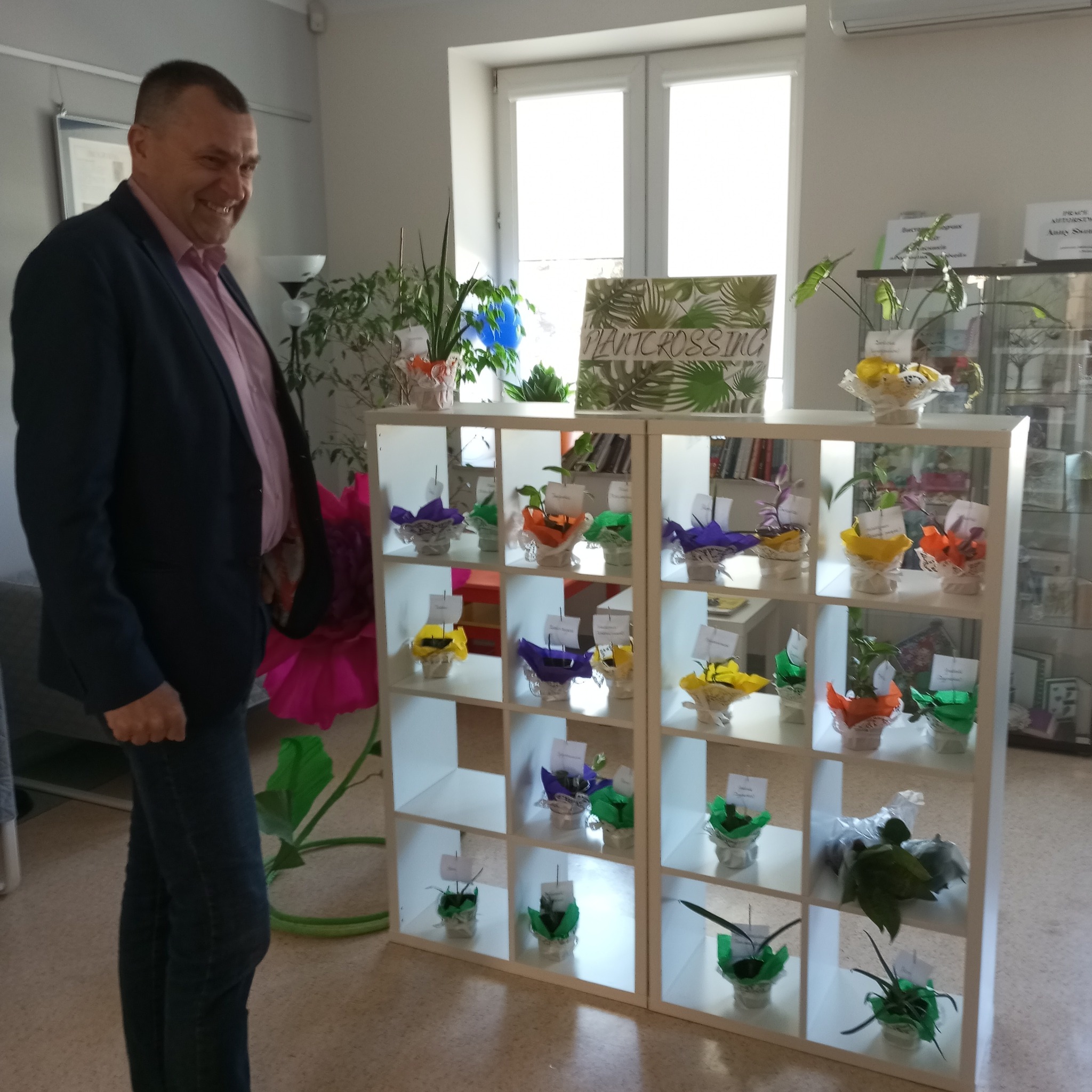 Mężczyzna stoi przed ekspozycją kwiatów doniczkowych