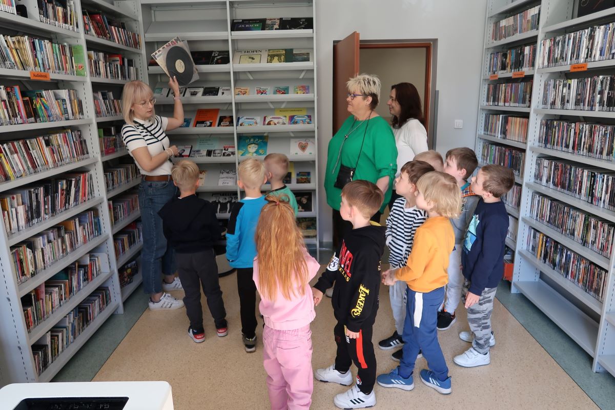 Dzieci zwiedzają pomieszczenie biblioteczne z płytami.