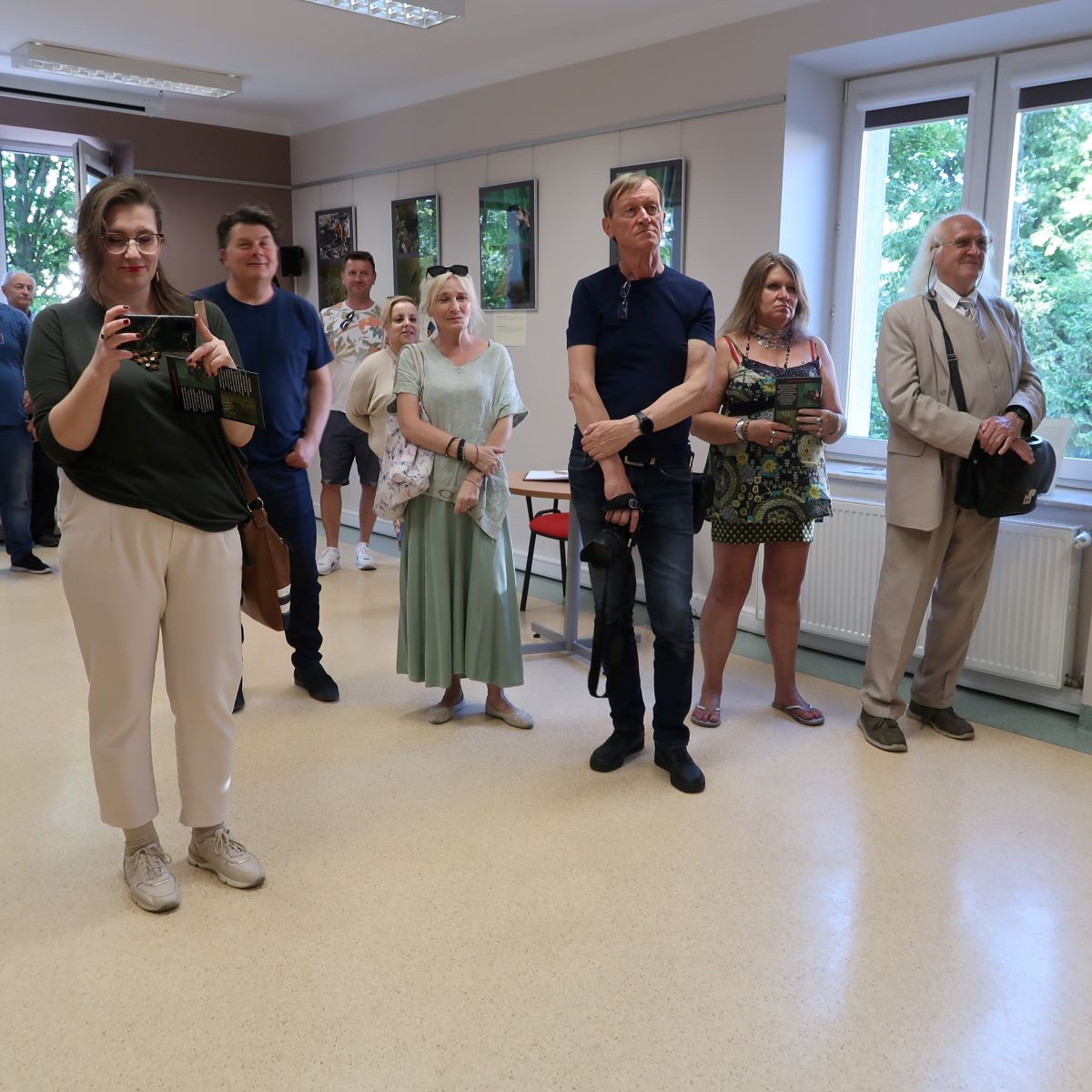 Grupa osób rozproszonych po sali wystawowej