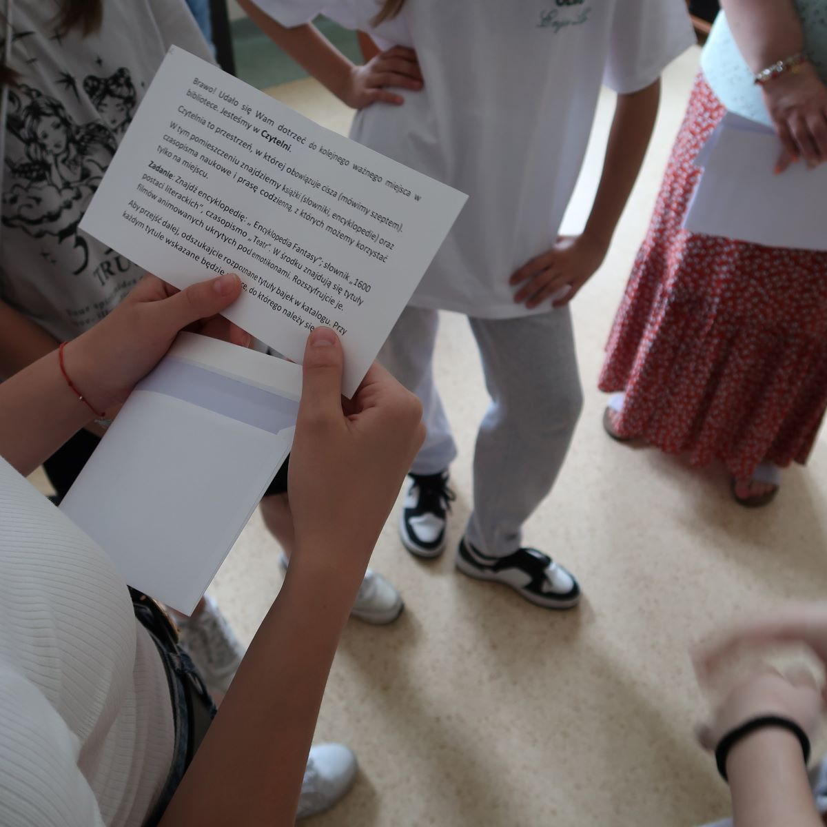 Dziewczynka odczytuje tekst zapisany na kartce papieru