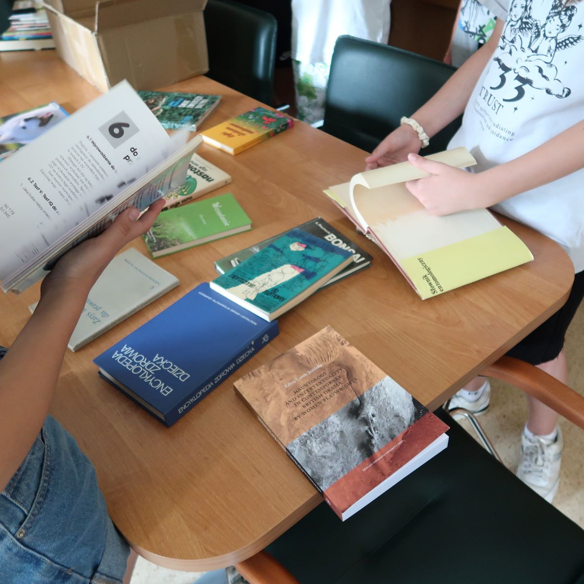 Młodzież ogląda książki rozłożone na stole