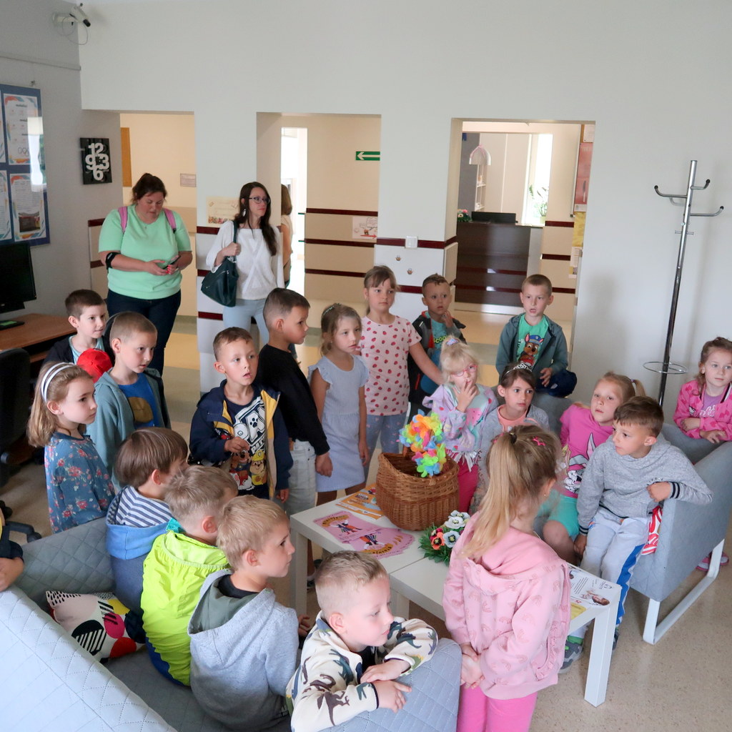 Grupa dzieci gromadzi się w pomieszczeniu bibliotecznym