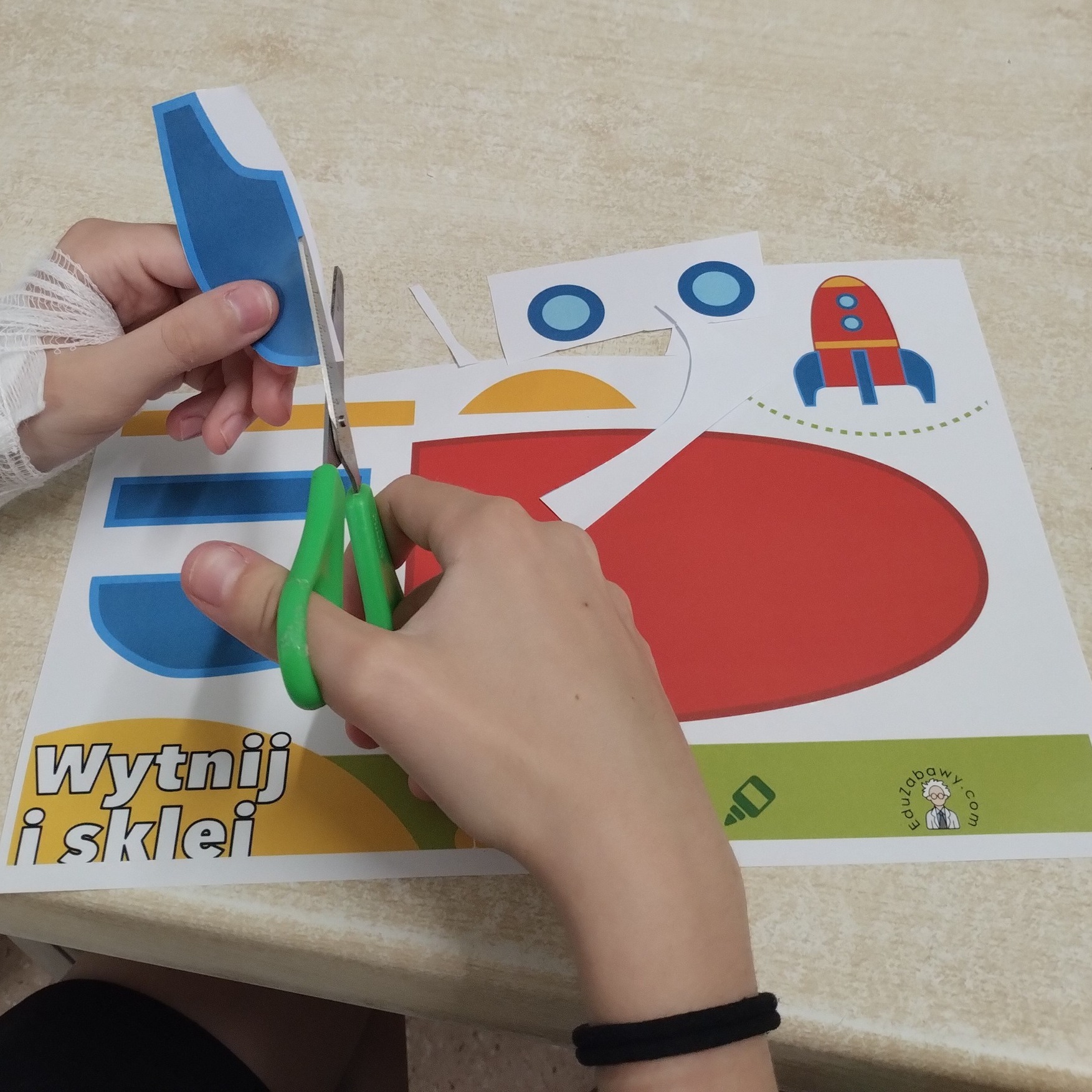Dziecięce rączki wycinają schemat rakiety kosmicznej