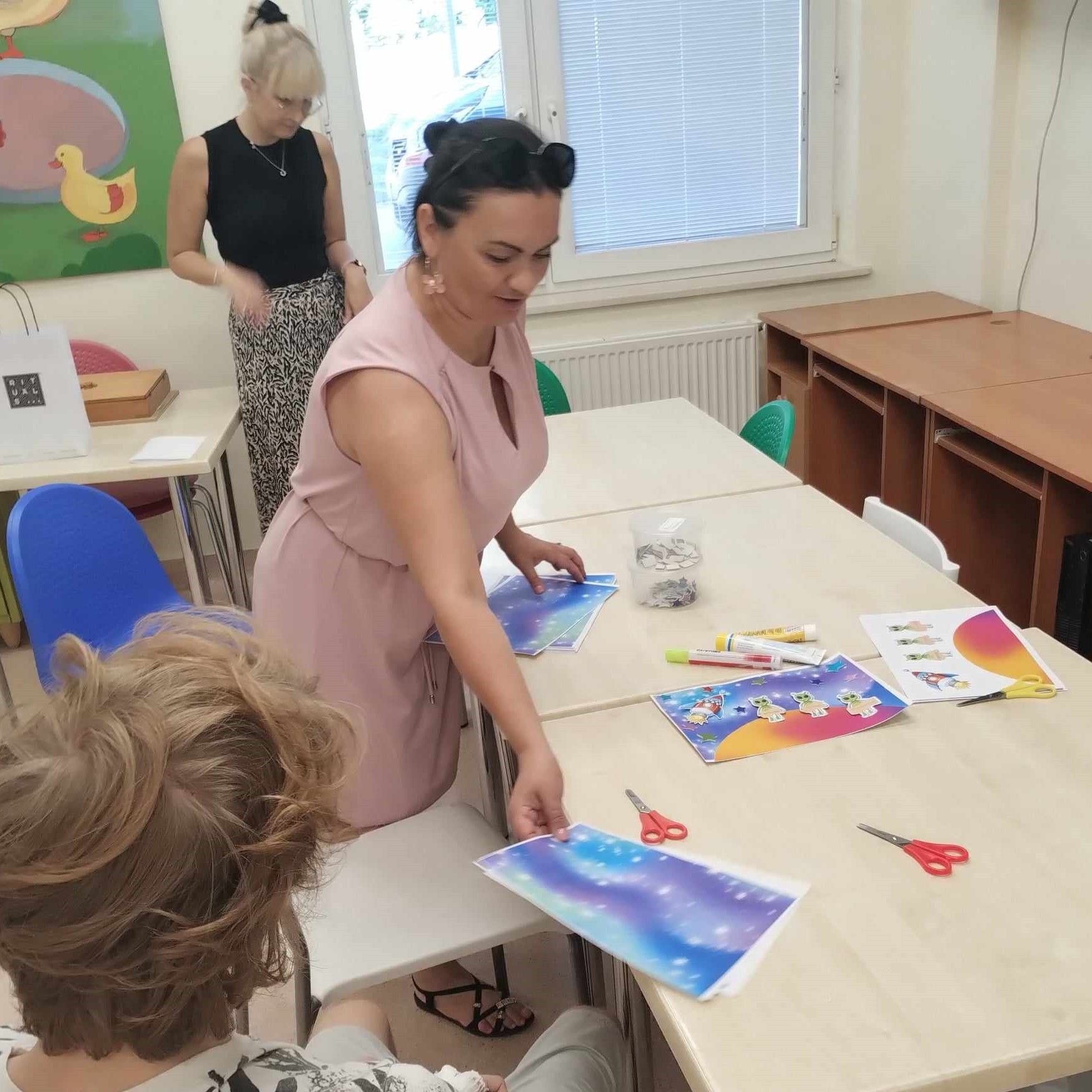 Pani rozdaje prace plastyczne dzieciom