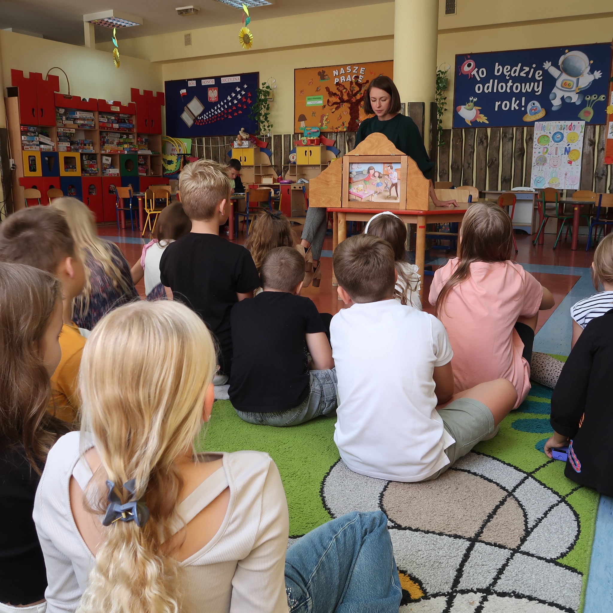 Pani prezentuje dzieciom obrazki teatrzyku kamishibai.