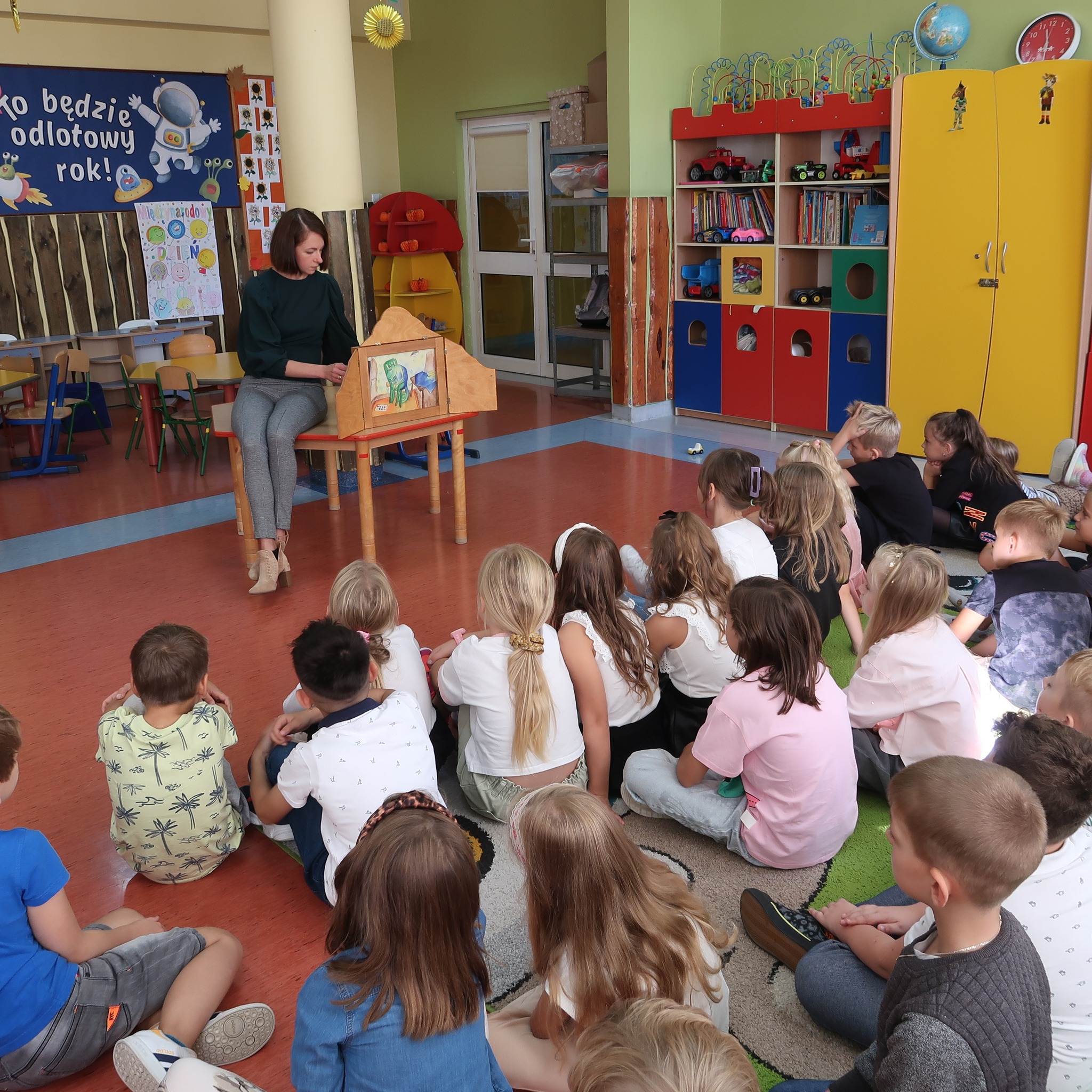 Pani prezentuje dzieciom obrazki teatrzyku kamishibai.