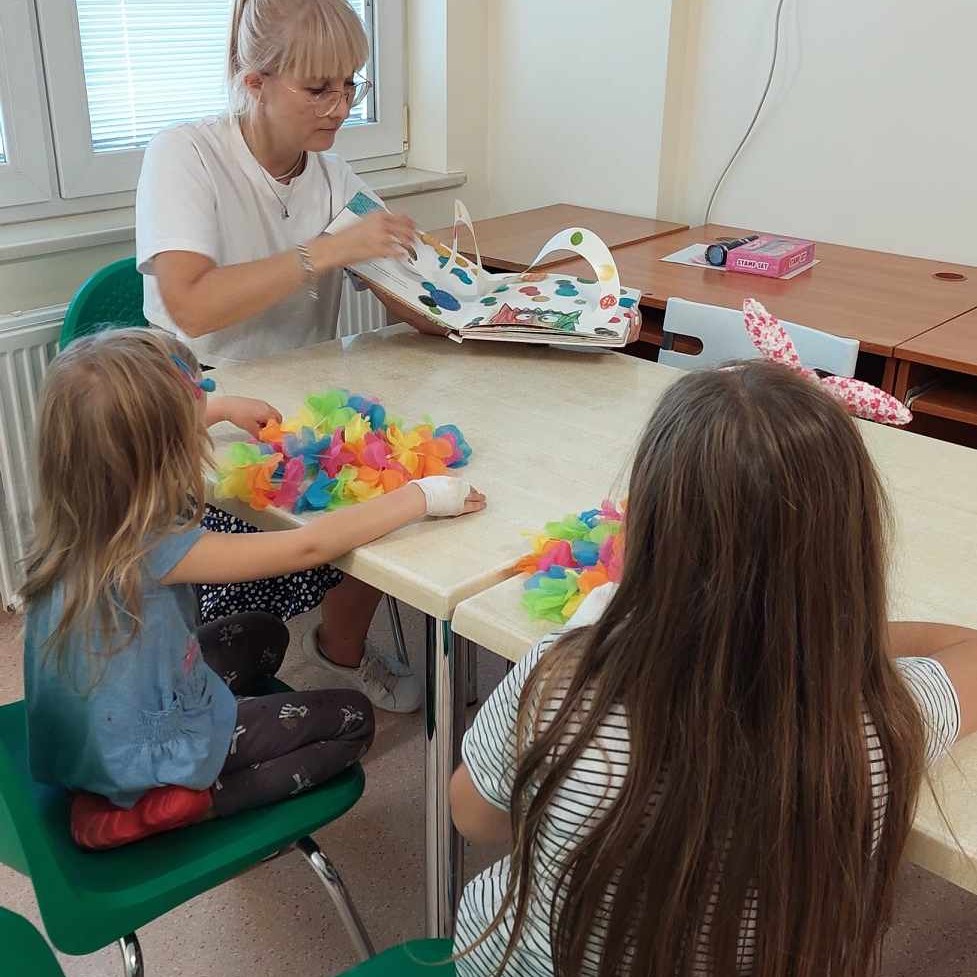 Pani pokazuje dzieciom ilustrację kolorowego potwora z książki