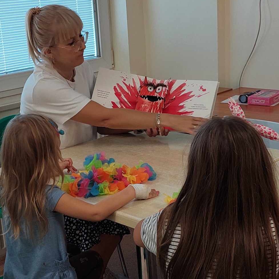 Pani pokazuje dzieciom ilustrację kolorowego potwora z książki