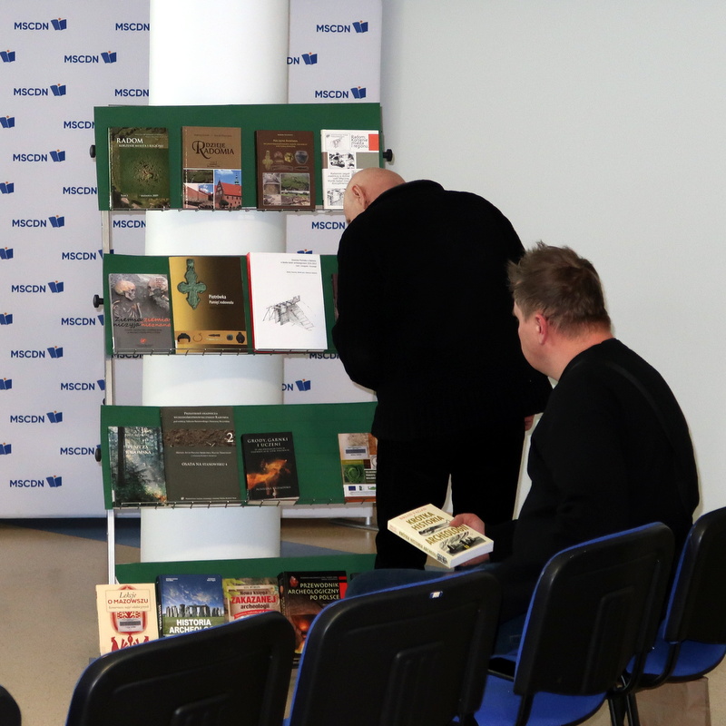zaczelo-sie-w-piotrowce-6 Dwaj starsi panowie oglądają wystawę wydawnictw książkowych poświęconych historii Radomia prezentowanej podczas spotkania pt. "Zaczęło się w Piotrówce".